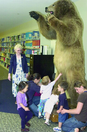 Taxidermied Alaskan brown bear standing on its hind legs with its forepaws raised, surrounded by small children and adults in Belk Library